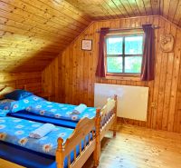 Wooden interior with wood-patterned flooring and two beds in a family house.