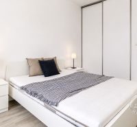 A bedroom with a bed and a wardrobe in a 2-room apartment, floor with wood decor.