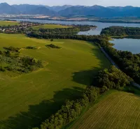 Liptovský Trnovec offers extensive greenery with a lake, surrounded by forest vegetation and fields.