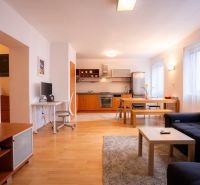 Living room with kitchen in a 4-room apartment, with a wooden decor floor and versatile furnishings.