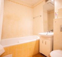 Bathroom in a 4-room apartment with a bathtub, sink, and toilet, light tiles.