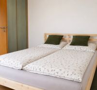 A bedroom with a double bed, pillows in a two-room apartment on a floor with a wooden decor.