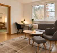 Living room in a 2-room apartment with comfortable seating and a table.