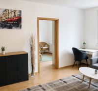 Living room in a two-room apartment with a wooden-patterned floor and a picture of Paris.