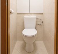 A bathroom in a 2-room apartment with beige tiles and a toilet.