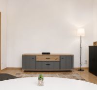 Living room with wood-patterned flooring, furniture, and a floor lamp in a two-room apartment.