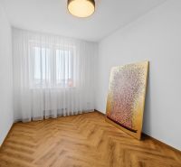 A bedroom in a 3-room apartment with a painting, white curtains, and a floor with a wooden design.