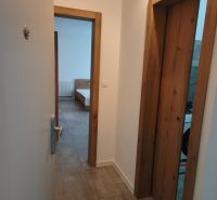 A hallway in a one-room apartment with tiles and wooden door frames.