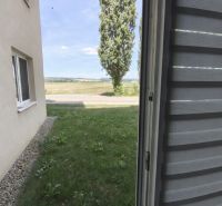 A view from the window of a studio apartment in Zlaté Moravce overlooking the lawn and a tree.