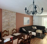 Living room in a family house with a sofa, dining table, and wooden decor flooring.