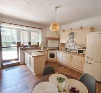 A kitchen in a family house with a wooden decor floor and light furniture.