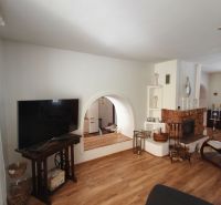Living room with a fireplace in a family house, floor with wooden decor, TV on a stand.