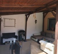 Covered terrace of a family house in Mankovce with rattan furniture and a fireplace.
