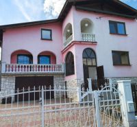 A family house in Mankovce with a pink facade, a floor, and a wrought iron fence.
