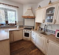 A kitchen with wood-patterned flooring, white cabinets, and tiles in a family house.