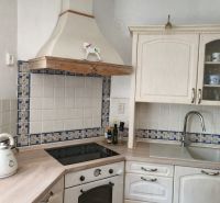 White kitchen with a cooktop, extractor hood, and wooden decor flooring in a family house.