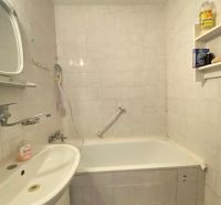 A bathroom with a bathtub, sink, and white tiles in a 4-room apartment.
