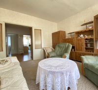 Living room in a 4-room apartment with a carpet and wooden furniture.