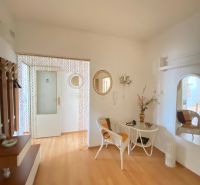 Interior of a 4-room apartment with a wooden decor floor, decorative mirrors, and wicker chairs.