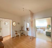 Interior of a 4-room apartment with a wooden decor floor, chair, and mirrors.