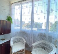 Loggia with wicker chairs and a view from a 4-room apartment with a wooden decor floor.