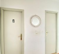 A hallway in a 4-room apartment with a wooden decor floor and two doors.