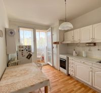 A kitchen in a 4-room apartment with a glass-enclosed balcony and a wooden decor floor.