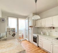 A kitchen in a 4-room apartment with white cabinets and a wooden decor floor.