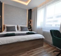 A bedroom with a wood-decor floor and a comfortable bed in a three-room apartment.