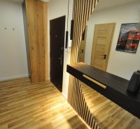 A hallway in a 3-room apartment with a floor featuring a wooden design and wooden doors.