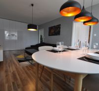 Dining room in a 3-room apartment with wood-patterned flooring and stylish lighting.