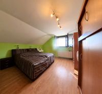 Attic room with a bed, wardrobe, and wooden decor flooring in a family house.
