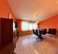 Living room in a family house with orange walls and black chairs.