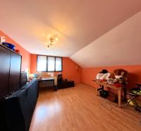 Attic room with a desk, sofa, and wooden decor flooring.