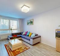 Living room in a 3-room apartment with a sofa, an aquarium, a plant, and a floor with a wooden decor.