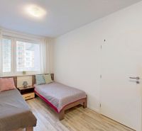 Two beds with colorful pillows and a wooden decor floor in a three-room apartment.