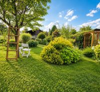 A garden by the cottage in Žilina, with a gazebo, a chair, and plenty of greenery.
