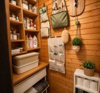 A cozy pantry in a log cabin with practical shelves, an organizer, and decorative plants.