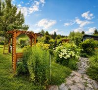 A garden by the cottage in Žilina with a wooden pergola and flower beds.