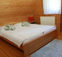 A bedroom in a cabin with wooden paneling, a bed, and a floor with a wooden decor.