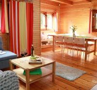 A cabin with wooden decor, comfortable furniture, a dining table, and a glass of wine.