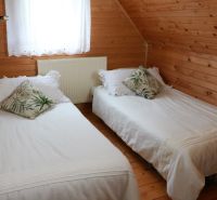 A cabin bedroom with wooden paneling, two beds, and decorative pillows.