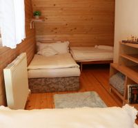 Wooden paneling of the room in the cottage, two beds, floor with wooden decor, bookshelf.