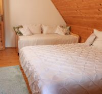 A bedroom in a cottage with two beds, an attic, and a floor with a wooden decor.