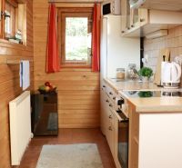 A kitchen in a cabin with wooden decor, white appliances, and a window with a view.