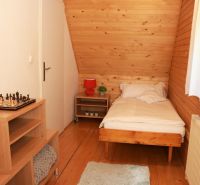 Single room with wood-patterned flooring, a chessboard on the table, and a window with a white curtain.
