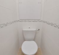 White toilets with patterned tiles and narrow space in commercial premises.