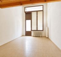 An empty commercial space with a window and a radiator, floor with wooden decor.