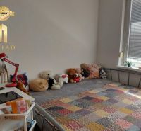 A room in a one-room apartment with a bed, a colorful blanket, and plush toys.