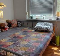 A bedroom in a studio apartment with a bed and a pile of stuffed toys on the bed.